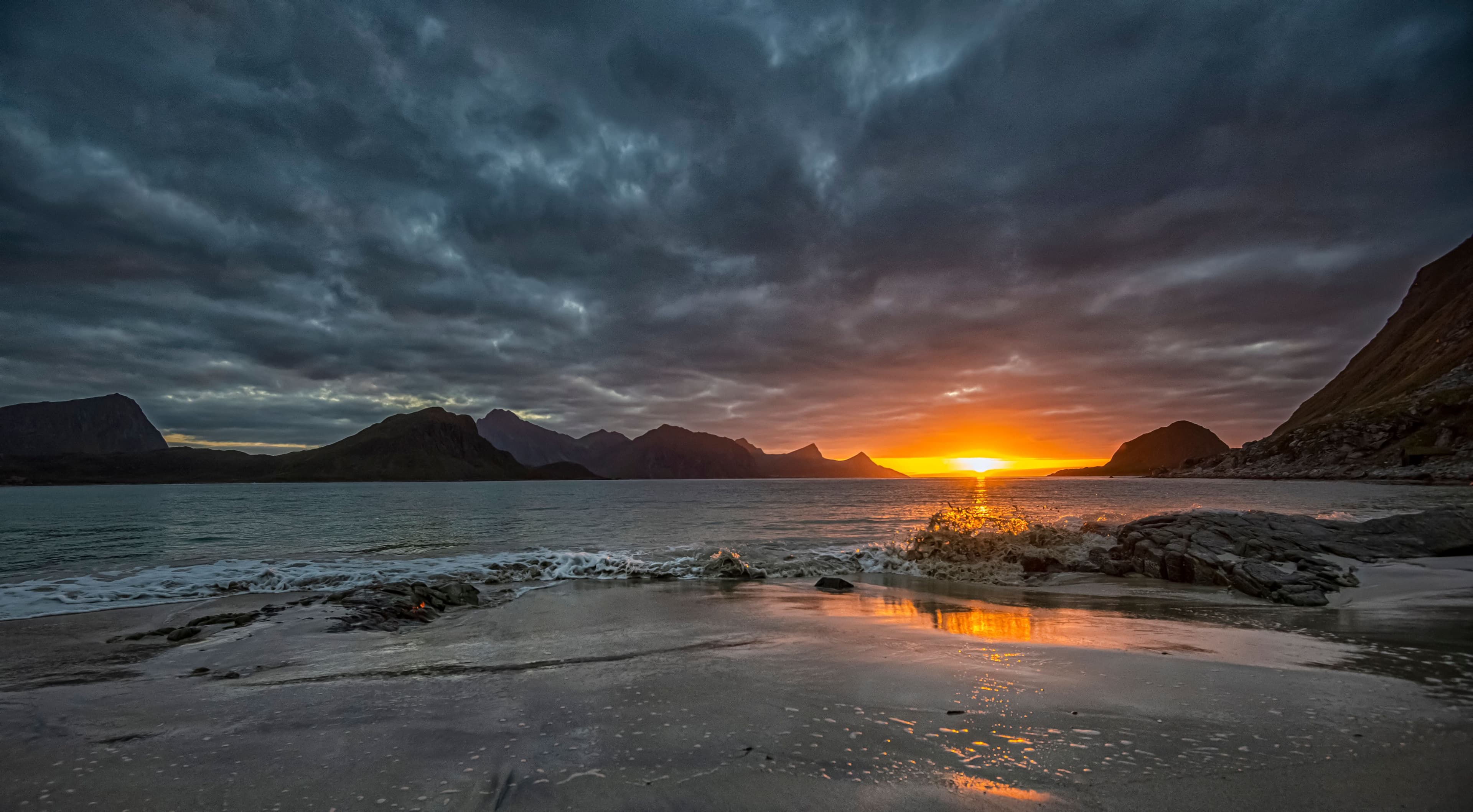 A quiet Arctic coastline at sunset with mountains in silhouette